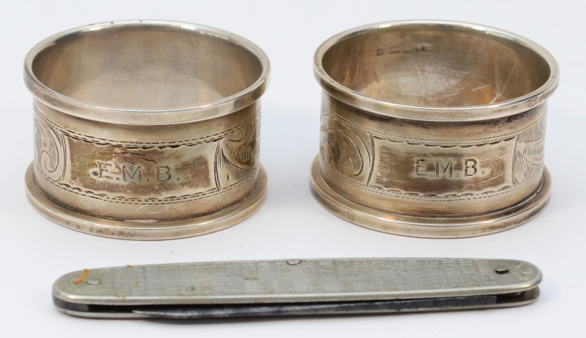 A pair of silver napkin rings, Birmingham 1932, both with E.M.B. initials and a metal Kings and