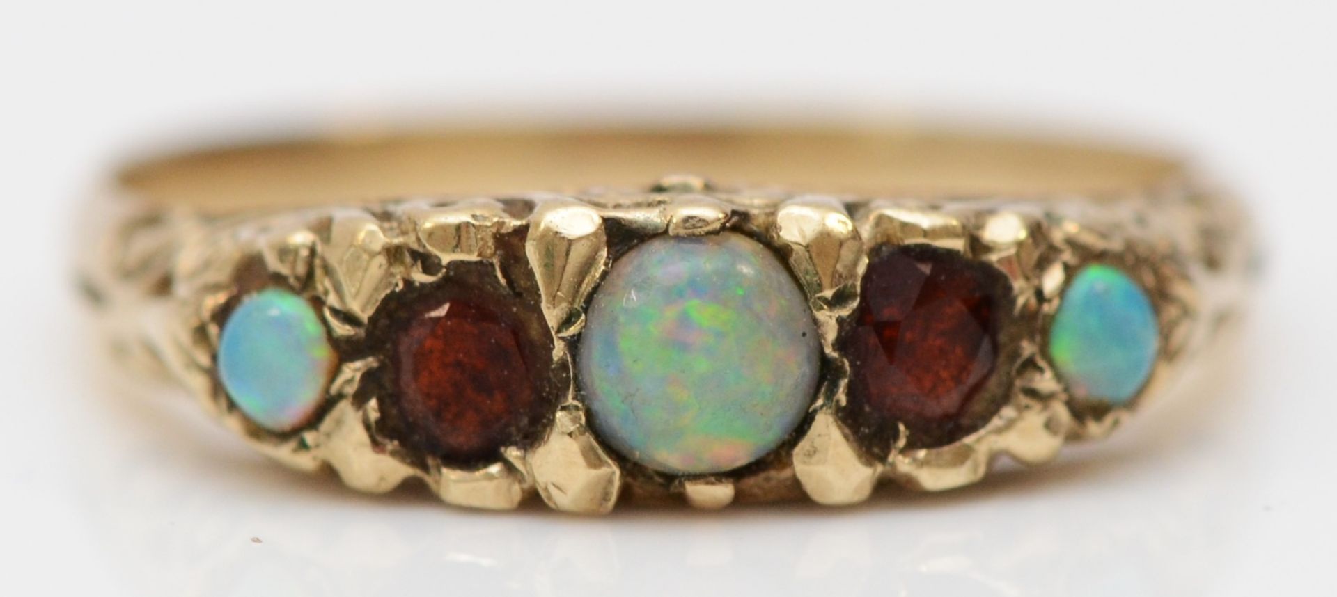 A vintage unmarked gold opal and garnet five stone ring, carved setting, N, 2gm