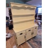 A painted pine kitchen dresser, the shaped top having two tier panelled plate rack over three frieze