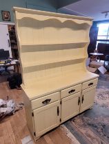 A painted pine kitchen dresser, the shaped top having two tier panelled plate rack over three frieze