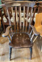 An early 20th century beechwood slat-back fireside armchair on turned supports with central