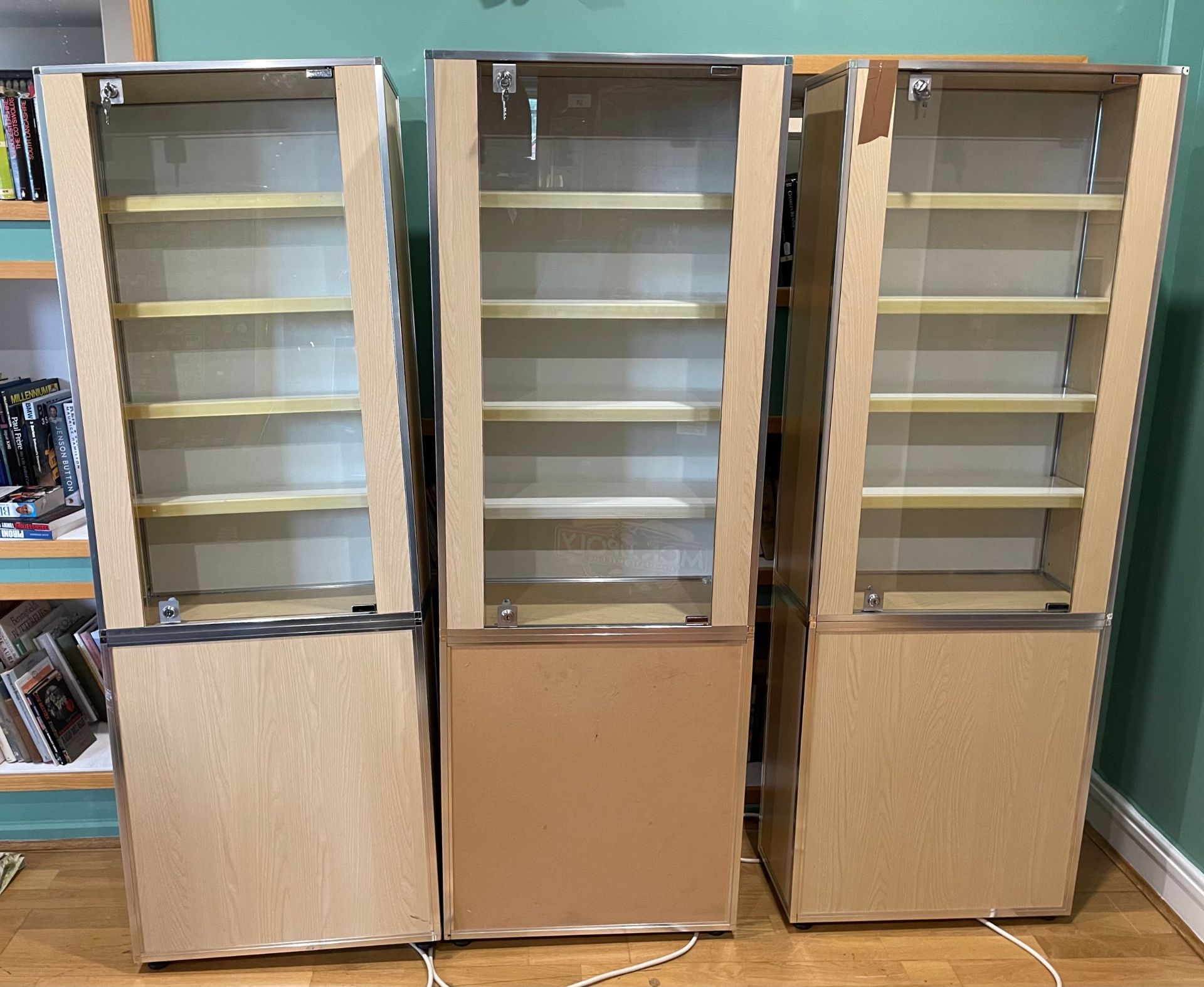 Three modern ex-shop illuminated display cabinets, having single lockable glazed doors opening to