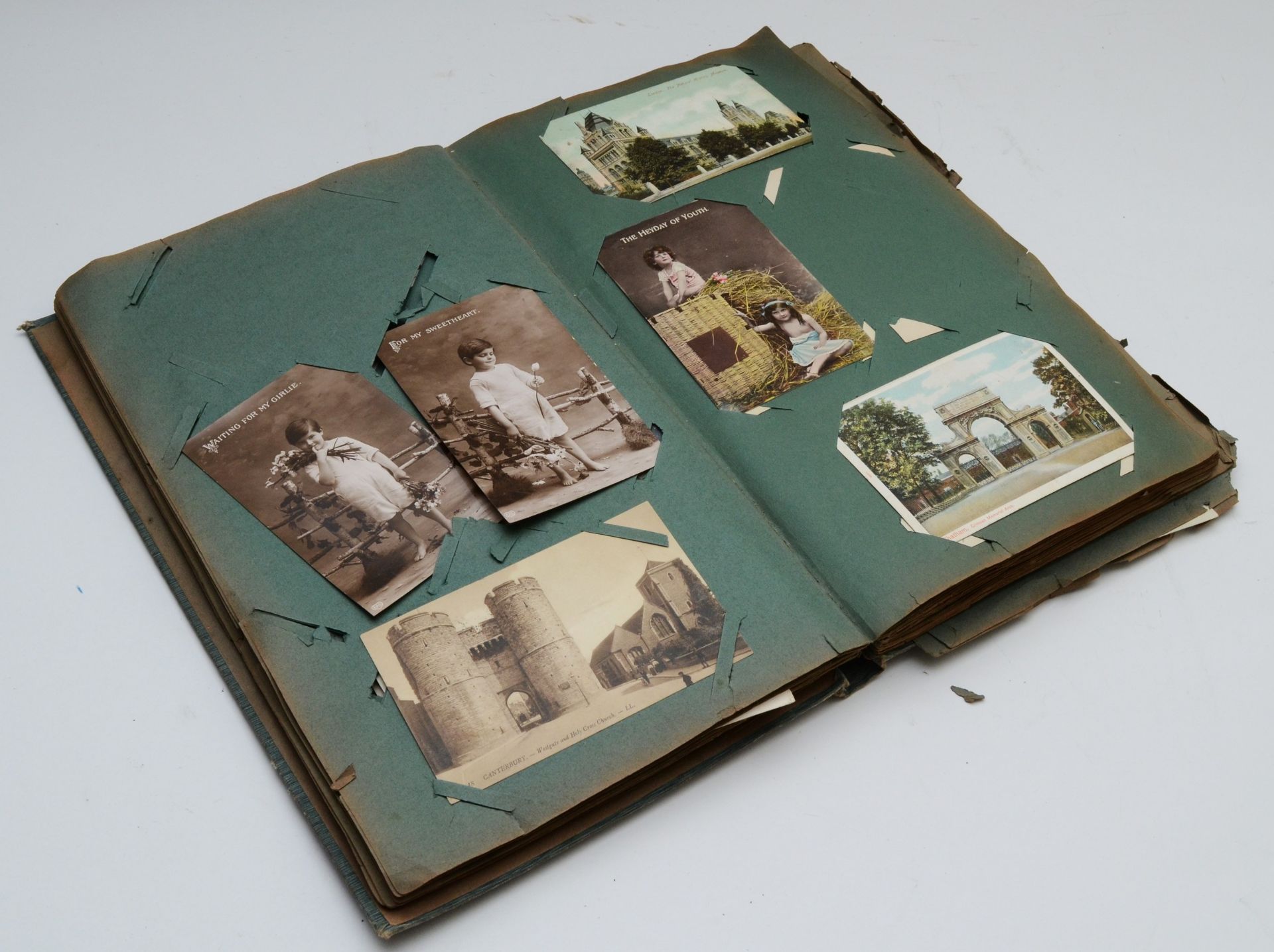A postcard album and contents including over two hundred topical postcards, dating from early to mid