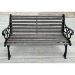 A two seater garden bench, with slatted wood seat and combined back, raised on painted cast iron