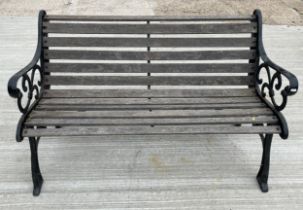 A two seater garden bench, with slatted wood seat and combined back, raised on painted cast iron