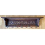 An early 20th century oak wall shelf, having carved frieze floral relief, with five brass hooks.