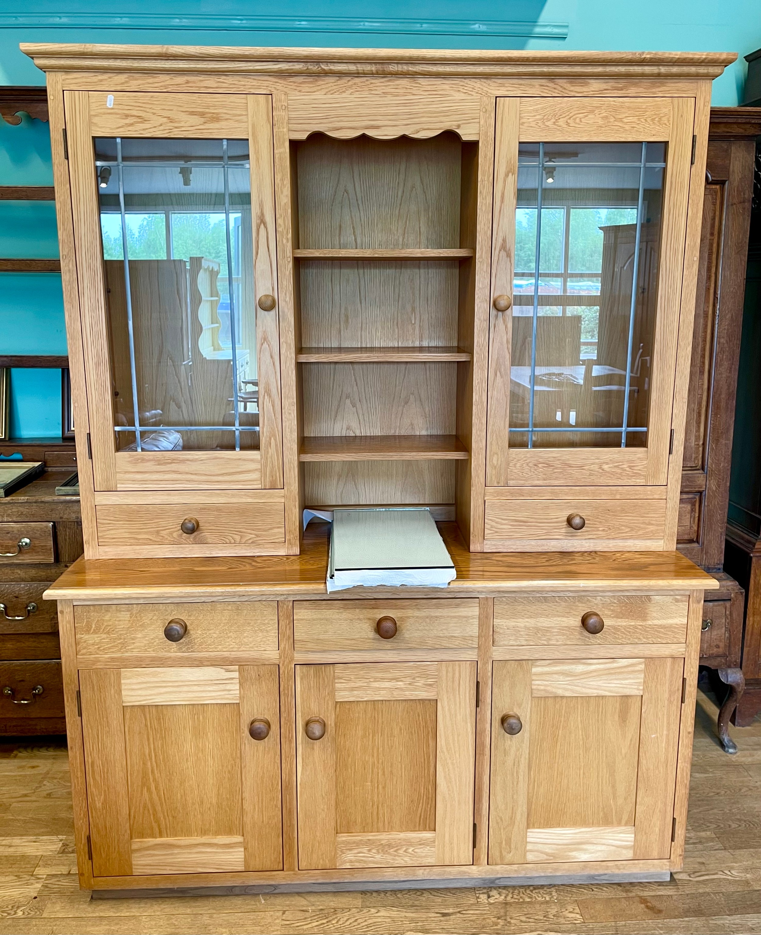 A modern light oak kitchen dresser,the flared cavetto cornice over a central bank of three fitted