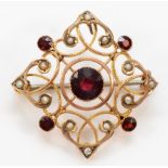 An Edwardian 9ct rose gold milligrain collet set garnet and half pearl brooch pendant, lacking bail,