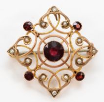 An Edwardian 9ct rose gold milligrain collet set garnet and half pearl brooch pendant, lacking bail,