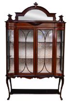 Edwardian inlaid mahogany display cabinet, the central arched mirror plate within a carved scroll