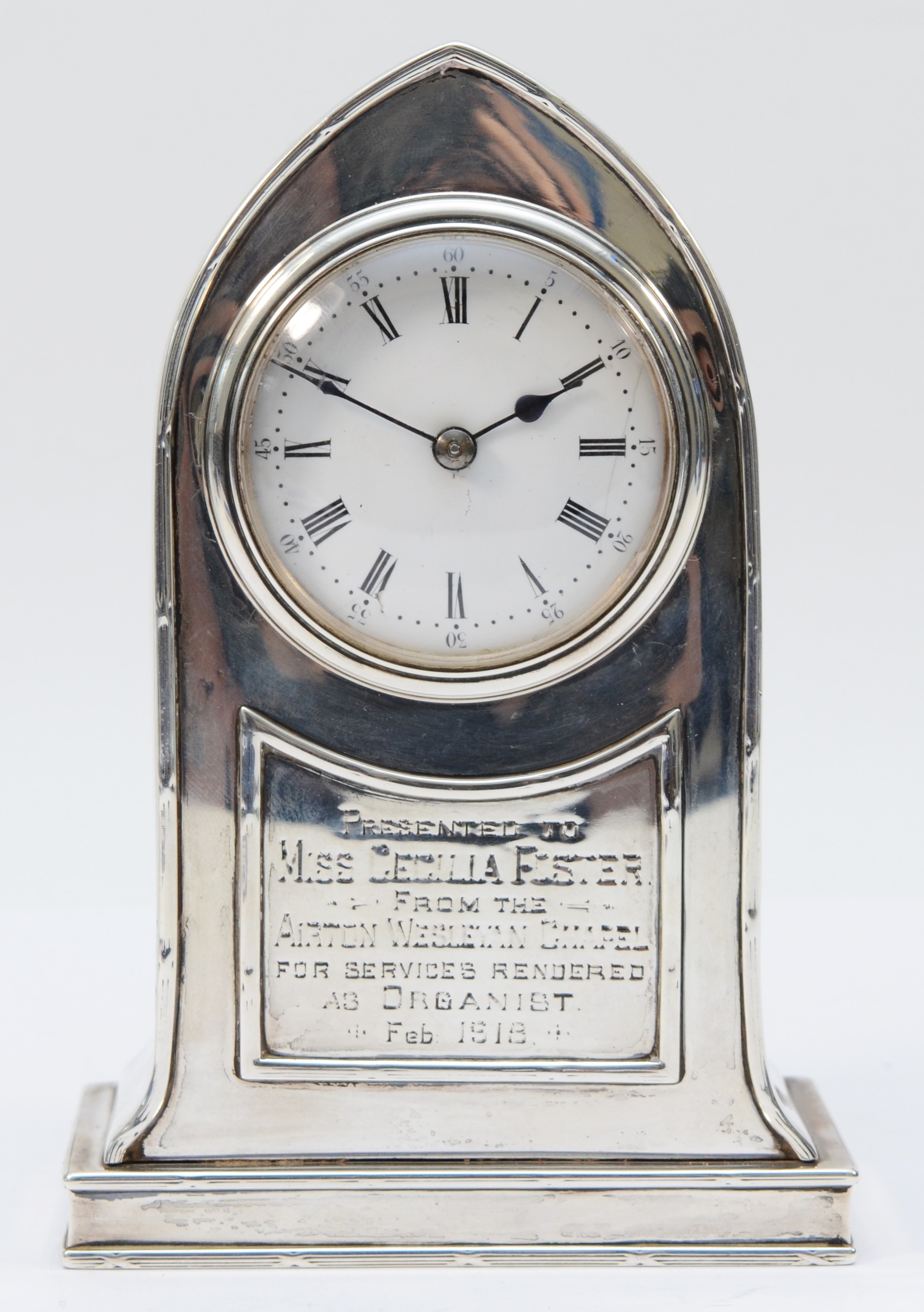 An Edwardian silver presentation desk clock, Birmingham 1907, of arched form, white enamel dial with