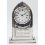 An Edwardian silver presentation desk clock, Birmingham 1907, of arched form, white enamel dial with