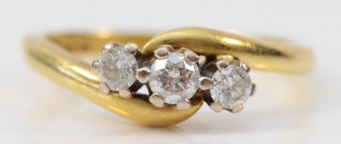 An 18ct gold and brilliant cut diamond crossover three stone ring, stated weight 0.33cts, L, 3.5gm