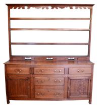 A 19th century Georgian oak dresser, projecting cornice over shaped apron and three-tier plate rack,