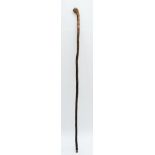 An Oriental walking stick of tapering form, the handle carved with the head of a Chinese Immortal,