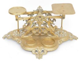 Set of late Victorian cast brass postal scales with ornate figural decoration on fleur-de-lis shaped