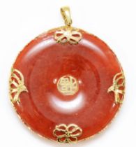 A Chinese 14K gold mounted reddish/brown jadeite disc pendant, diameter 36mm