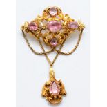 A Victorian unmarked gold foiled pink gemstone drop brooch, with foliate scroll frame and swag chain
