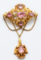 A Victorian unmarked gold foiled pink gemstone drop brooch, with foliate scroll frame and swag chain