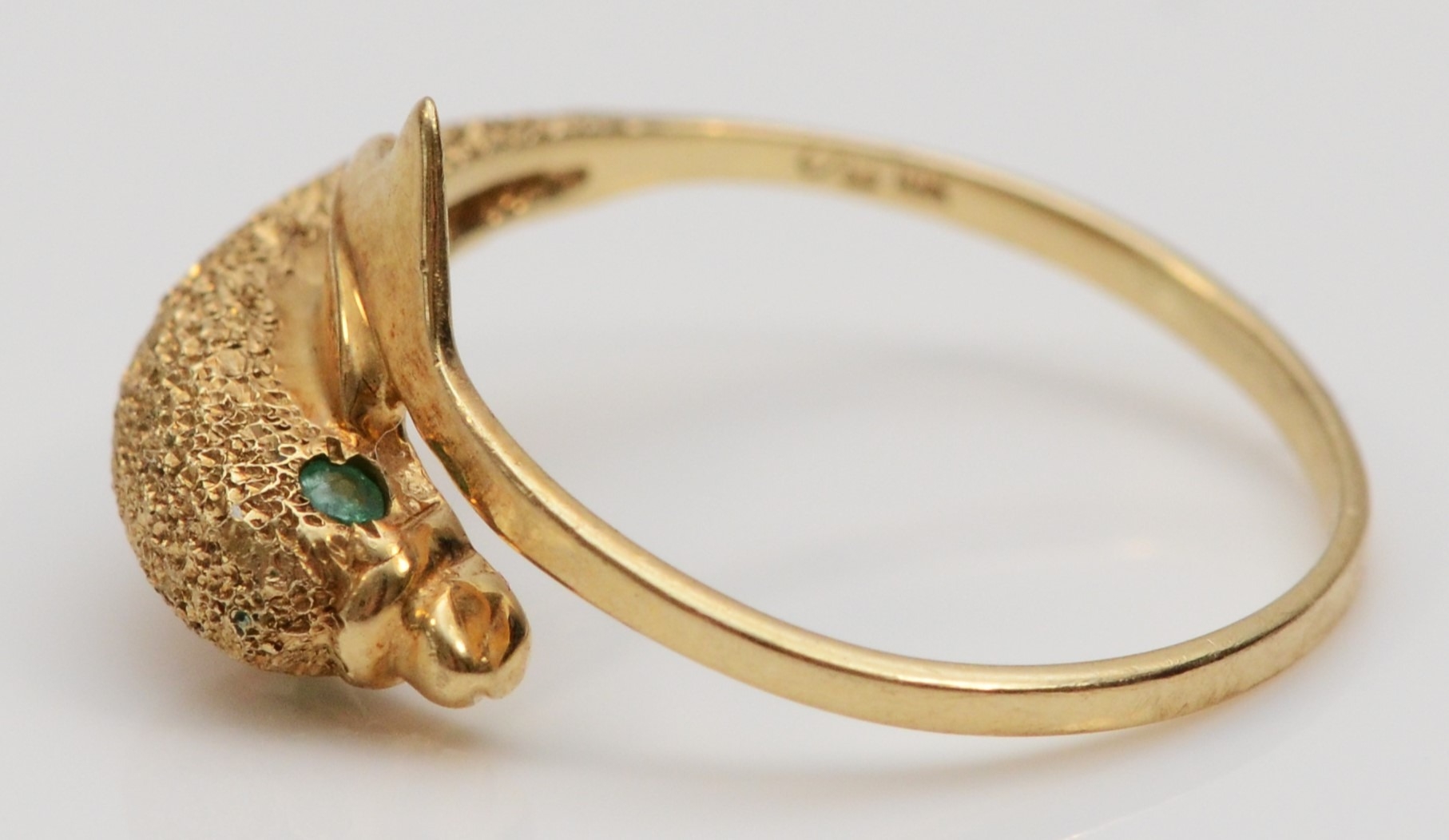 A 9ct gold textured dolphin ring, emerald set eyes, N, 1.6gm