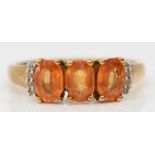 A 9ct gold three orange gemstone ring, white stone set shoulders, L 1/2, 2.2gm