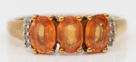 A 9ct gold three orange gemstone ring, white stone set shoulders, L 1/2, 2.2gm