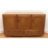 An Ercol blond elm Windsor sideboard, model 429, with a two-door cupboard and adjustable shelf,