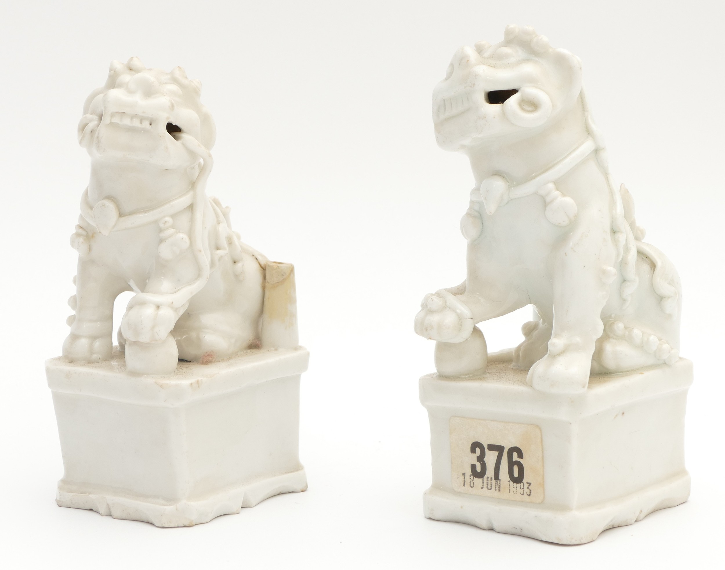 A pair of Chinese blanc de chine porcelain figures of a Dog of Fo, modelled seated with one paw