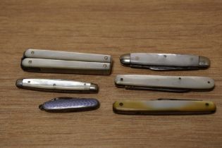 A selection of Mother-of- Pearl mounted pen knives and a miniature lilac guilloche enamel example.