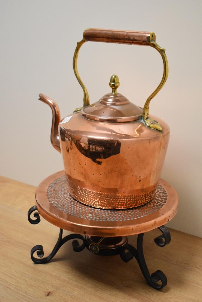 A vintage copper and brass kettle, sold with a heated copper and iron trivet.