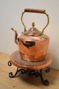 A vintage copper and brass kettle, sold with a heated copper and iron trivet.