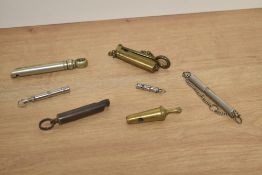 A selection of vintage whistles, dog whistles and a peculiar brass inspection glass or similar.