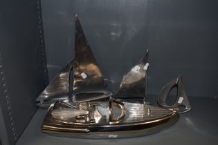 Three stylised aluminium sailing boat studies and a caste metal boat.