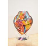 A heavy multi coloured mottled art glass vase, sat on clear glass foot.