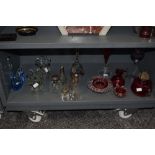 A selection of glassware, including cranberry glass oil lamp base, jug and pinch pots, blue art