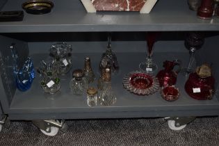 A selection of glassware, including cranberry glass oil lamp base, jug and pinch pots, blue art