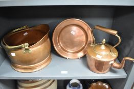 A copper coal helmet with brass handle, a copper charger and a copper kettle.