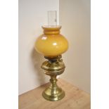 An early 20th Century oil lamp, having an amber coloured glass shade, chimney, and brass body,