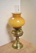An early 20th Century oil lamp, having an amber coloured glass shade, chimney, and brass body,