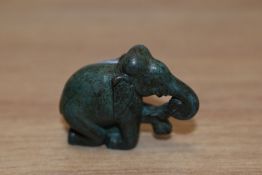 A bronze elephant in kneeling position, having initials DM etched to foot.