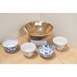 Four 20th century blue and white tea bowls and a larger natural stone bowl with carved archaic