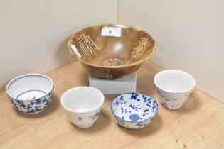 Four 20th century blue and white tea bowls and a larger natural stone bowl with carved archaic