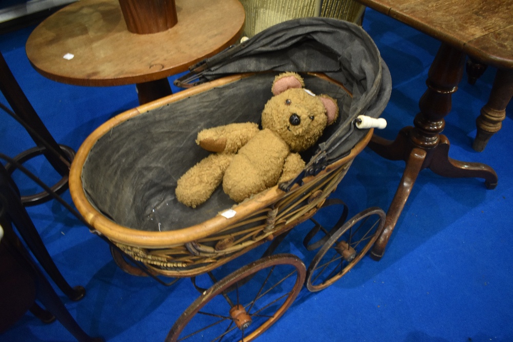A reproduction Victorian style dolls pram and vintage teddy bear