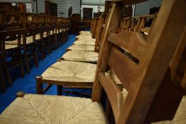 A set of six rush seated chapel chairs having ladder backs, with hymn/prayer book shelves