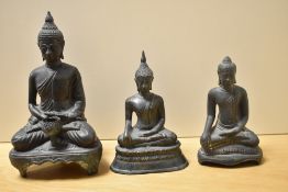 Three 19th Century Eastern cast metal seated Buddha ornaments, the largest depicting a Buddha seated
