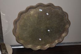 An Eastern brass tray, of scalloped oval outline, with engraved detail, and measuring 78cm long