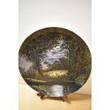 A 20th Century studio pottery charger, decorated with a moonlit scene depicting sheep in a field,