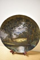 A 20th Century studio pottery charger, decorated with a moonlit scene depicting sheep in a field,