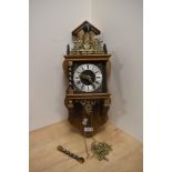 A vintage wall clock, having oak case, brass decorations and Roman numerals to face.