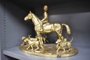 A 20th Century solid brass figural ornament, in the form of a huntsman on horseback, with hounds,